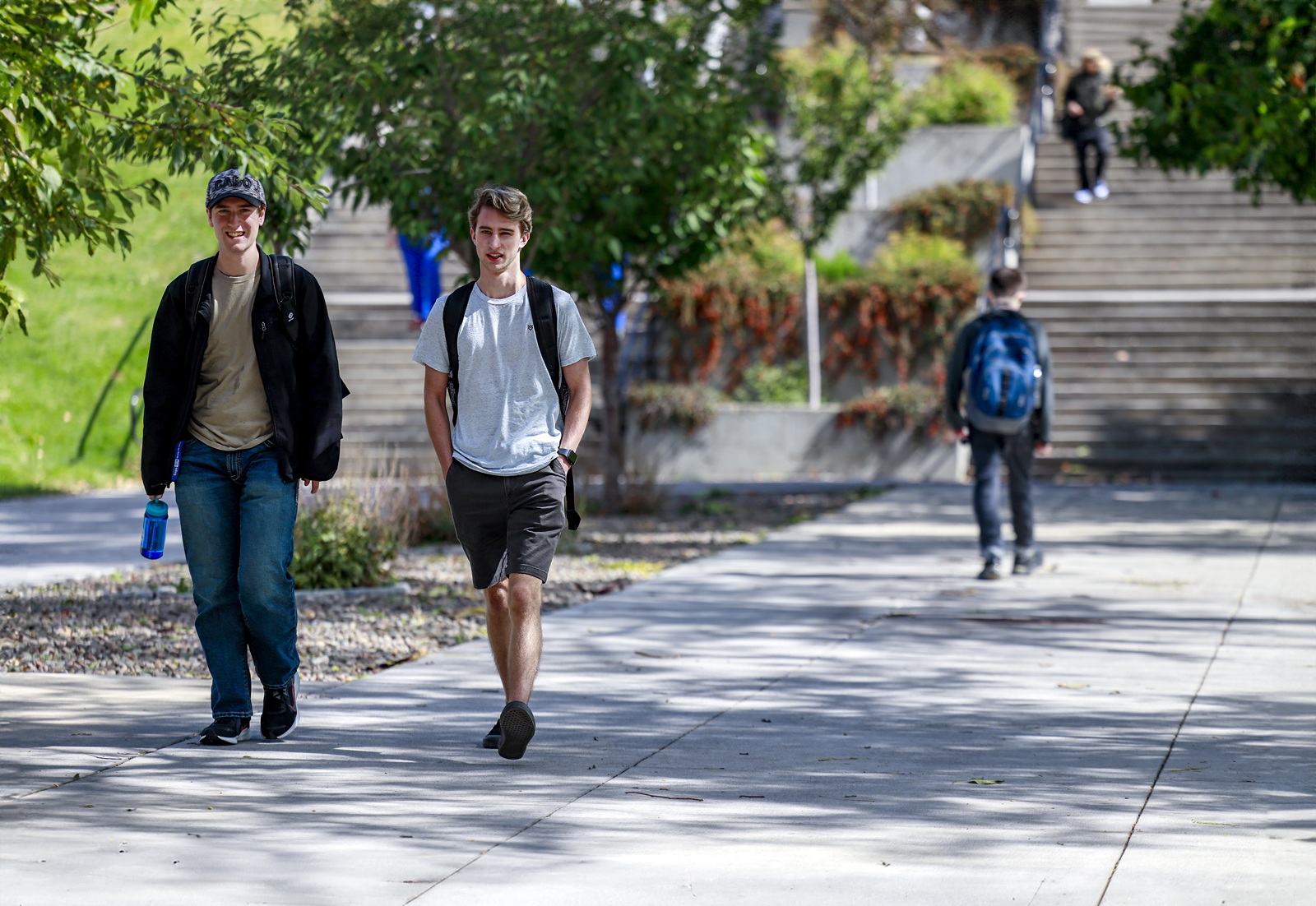 Students walking across campus with hill and staircase behind