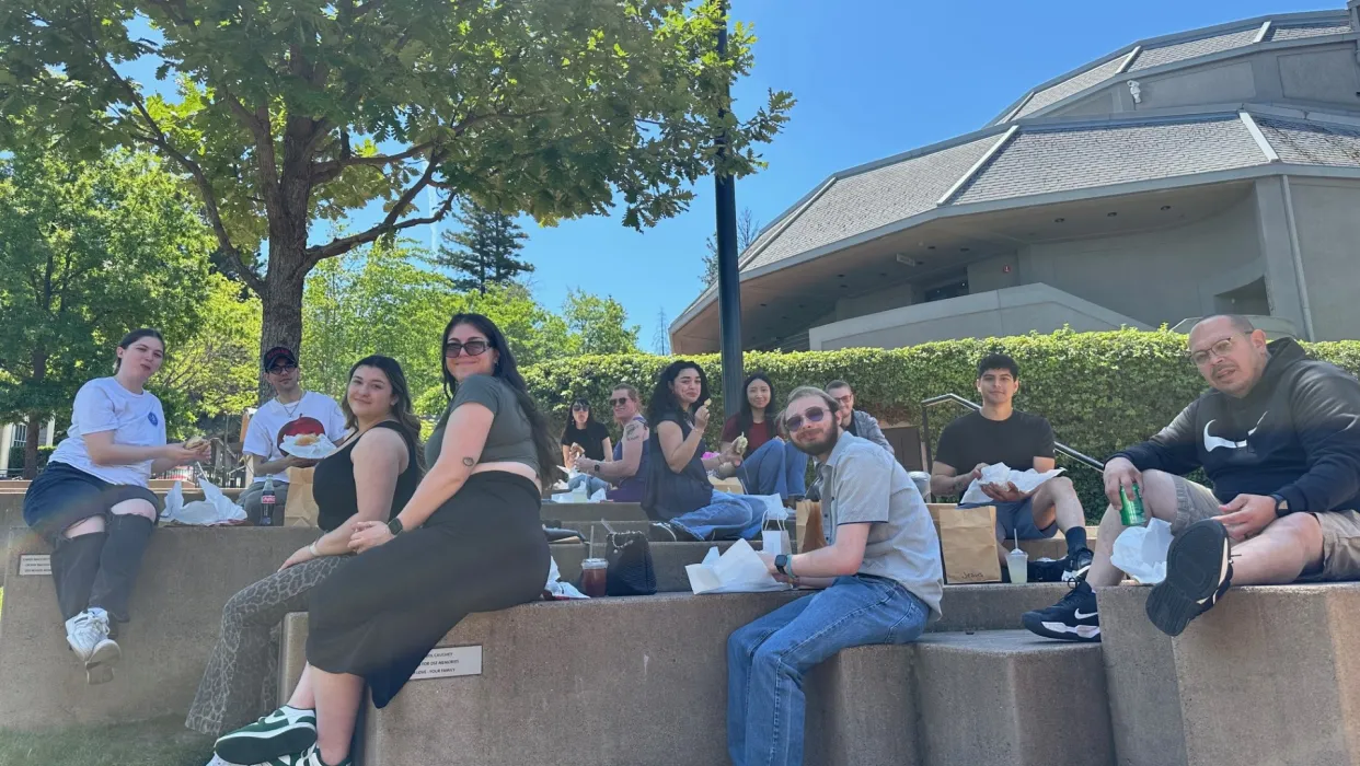 Students sitting on concrete steps eating lunch and smiling
